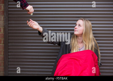 Ragazza adolescente di dormire sulla strada essendo dato soldi Foto Stock