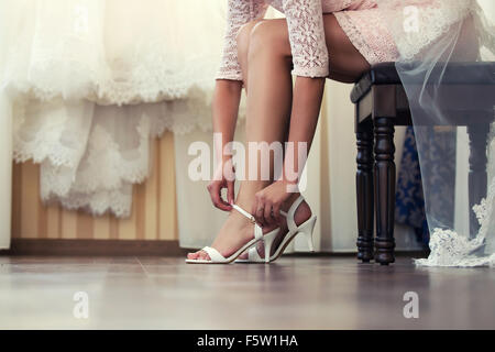 Sposa mette le sue scarpe al mattino all'interno Foto Stock