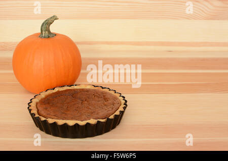 Mini torta di zucca con piccola zucca arancione su uno sfondo di legno, con spazio di copia Foto Stock