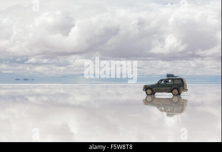 Auto sulla superficie riflessa del Salar de Uyuni lago in Bolivia Foto Stock