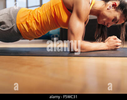 Ritagliato colpo di donna esercizio in palestra. Femmina muscolare facendo core allenamento sul tappetino fitness con copia spazio. Foto Stock