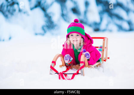 Bambina spalare la neve sulla home drive modo. Bellissimo giardino nevoso o cortile anteriore. Bambino con la pala a giocare all'aperto in inverno Foto Stock