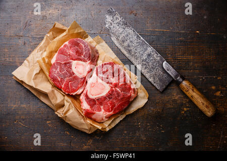 Crudo fresco di taglio trasversale di Stinco di vitello per la produzione di Osso Buco su sfondo di legno con carne cleaver Foto Stock