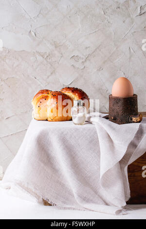 La prima colazione con un intero uovo sodo in eggcup in legno e pane fatto in casa serviti con sale sulla cassa di legno con un panno bianco sulla Pentecoste Foto Stock