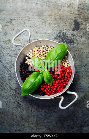 Vista aerea di coloratissimi essiccato mix di pepe e basilico in vaso su sfondo rustico Foto Stock