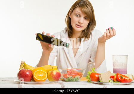 Giovane bella ragazza in accappatoio prepara piatti vegetariani insalata di verdure e verde isolato su sfondo bianco Foto Stock