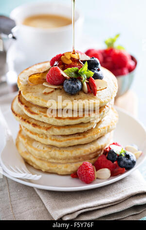Soffici pancake di avena stack con frutti di bosco freschi, caffè e sciroppo Foto Stock