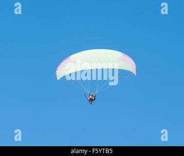 Due persone in parapendio in tandem volo contro il cielo blu sullo sfondo Foto Stock