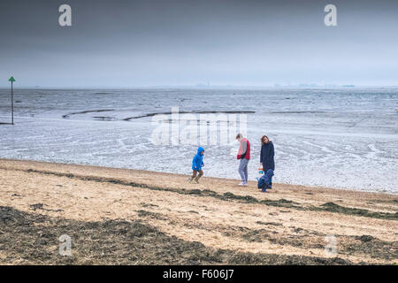 Una famiglia di brave il freddo sulla campana Wharf Beach a Leigh on Sea, Essex. Foto Stock