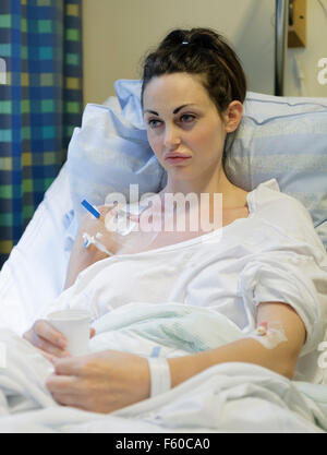Malati giovane donna posa nel letto di ospedale con catetere venoso centrale (CVC) essendo somministrati fluidi e la nutrizione per via parenterale (PN) modello di rilascio: Sì. Proprietà di rilascio: No. Foto Stock