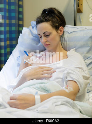 Malati giovane donna posa nel letto di ospedale con catetere venoso centrale (CVC) essendo somministrati fluidi e la nutrizione per via parenterale (PN) modello di rilascio: Sì. Proprietà di rilascio: No. Foto Stock