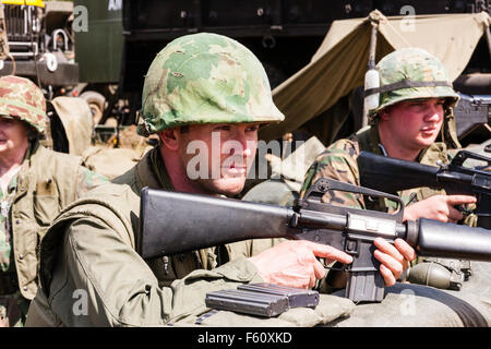 Guerra del Vietnam "Rolling Thunder" rievocazione gruppo. Due Marines in stand by, avviso in piedi in trincea, tenendo M16s, guardando. Close up. Foto Stock