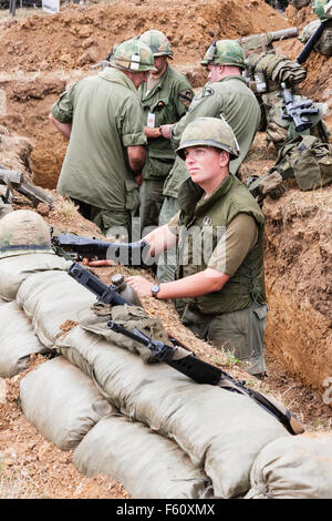 Guerra del Vietnam "Rolling Thunder" rievocazione gruppo. Guardando verso il basso in corrispondenza di quattro Marines in trincea, tre in chat e uno con smontaggio mitragliatrice. Foto Stock