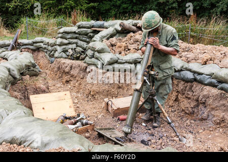 Guerra del Vietnam Rolling Thunder rievocazione gruppo. Marine, noi soldato, in sandbagged radicato in posizione di sparo, impostazione di scavo pesante mortaio. Foto Stock