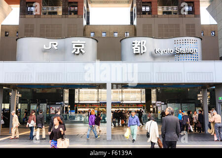 Giappone, Kyoto. Kyoto stazione ferroviaria ingresso principale con JR logo e il nome della stazione in entrambe le lingue inglese e giapponese mentre al di sotto, la gente camminare in e out. Foto Stock