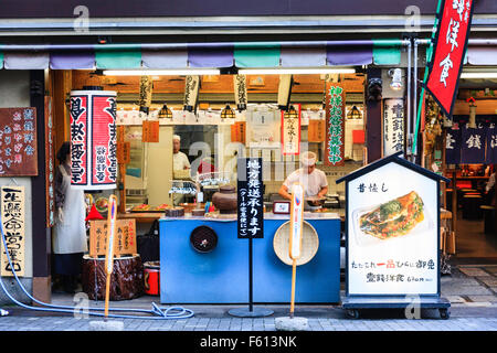 Giappone, Kyoto, Gion. Famoso Okonomiyaki ristorante, Issen Yoshoku. Vista frontale, esterno. Lo Chef all'interno di preparare del cibo su aprire il contatore. Foto Stock