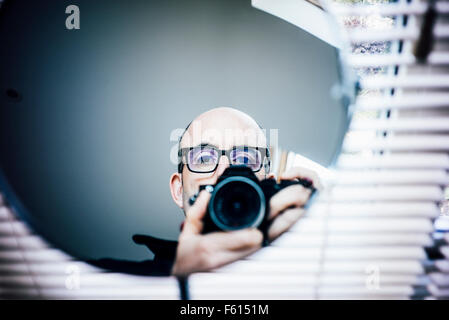 Un fotografo rivolto la sua fotocamera in uno specchio Foto Stock