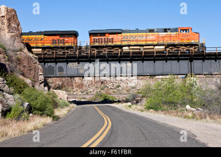 A Burlington Northern treno merci passa sopra la vecchia nazionale percorsi su strada e della Route 66 West di Kingman, Arizona. Foto Stock