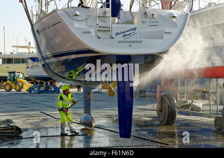 Yacht da crociera che viene sollevato e jet-lavata per rimuovere la incrostazione marina. Foto Stock