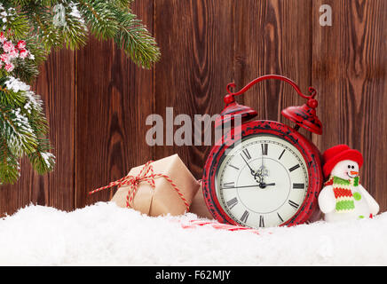 Regalo di natale scatole, sveglia, pupazzo giocattolo e abete nella neve Foto Stock