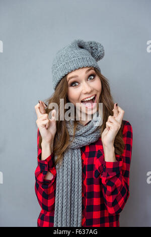 Bella divertente funny girl in maglia Sciarpa grigio e hat sorridente e dita incrociate Foto Stock