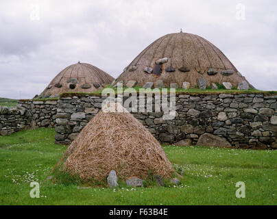 Arnol Blackhouse, isola di Lewis: stackyard & hipped termina di sod e tetti di paglia di interconnessione lungo le aree soggiorno & byre su R con fienile su L. Foto Stock