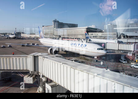 Uomo che guarda attraverso la finestra terminale per aereo Boeing 767-424(ER) con registrazione N77066 della United Airlines a Bruxelles Airpo Foto Stock