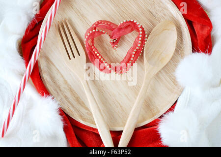 Forma di cuore sul piatto di legno con cucchiaio e forchetta Foto Stock