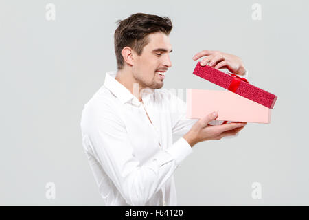 Felice allegro giovane ragazzo in maglia bianca cercando nel riquadro rosa Foto Stock