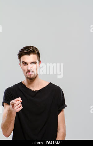 Giovane bello ragazzo affascinante in black t-shirt puntando su di voi Foto Stock