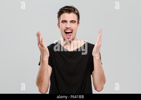 Ritratto di giovane bello carismatic man in black t-shirt urlando con le mani in alto Foto Stock