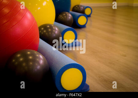 Una selezione di attrezzature da palestra che spaziano dalla sfera di pilates yoga a rotoli. Foto Stock