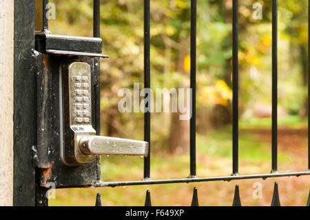 Una serratura con una tastiera e codice di sicurezza su un fuori del cancello che conduce ad un percorso di paese. Foto Stock