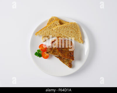 Due fette di arrosto di carne di maiale con pane tostato sulla piastra bianca Foto Stock