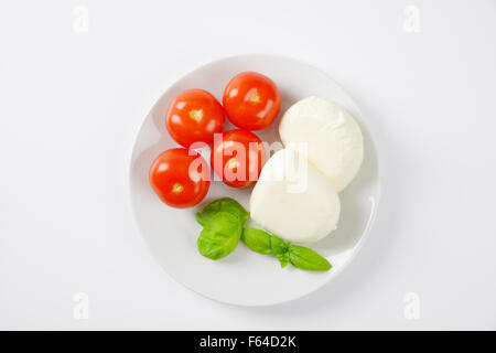 Mozzarella Fresca, basilico e pomodori - Ingredienti per insalata caprese sulla piastra bianca Foto Stock