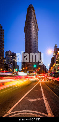 Flatiron Building con un cielo azzurro e auto sentieri di luce sulla Quinta Avenue al crepuscolo in Midtown Manhattan, a New York City Foto Stock