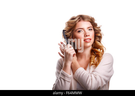 Giovane bella ragazza con i capelli ricci si raddrizza Pettine capelli. La ragazza con il trucco. Il parrucchiere. Foto Stock