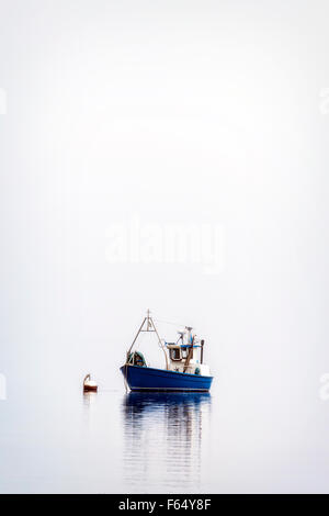 Una barca da pesca su un mare nebbioso Foto Stock