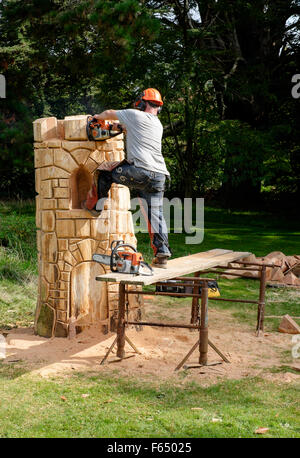 Un chainsaw scultore creando una torre la scultura da un tronco di albero a a Cranborne Chase Woodfair, Wiltshire, Regno Unito Foto Stock