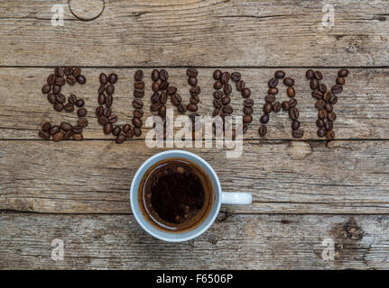 Tazza di caffè su sfondo di legno e domenica i chicchi di caffè Foto Stock
