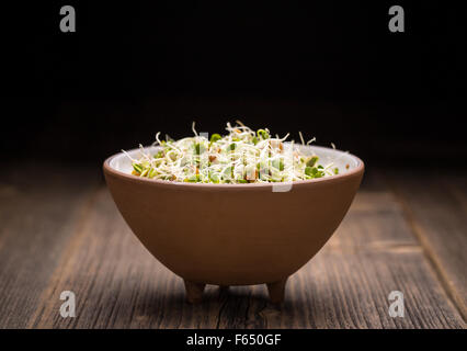 Mix di verde germogli giovani in vaso su sfondo di legno Foto Stock