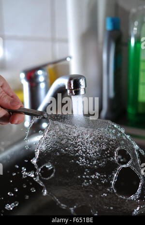 Illustrazione - un coltello viene lavato con acqua corrente del rubinetto a Dresda (Sassonia), Germania, 11 marzo 2013. Foto: Thomas Eisenhuth Foto Stock