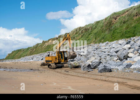 Escavatore meccanico lavorando sulla protezione delle coste di ballybunion golf in irlanda Foto Stock