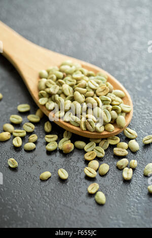 Chicchi verdi di caffè in cucchiaio di legno Foto Stock