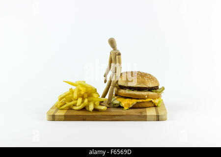 Il burattino di legno in piedi su un hamburger, guardando alcune patate fritte Foto Stock