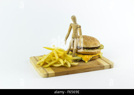 Il burattino di legno in piedi su un hamburger, guardando alcune patate fritte Foto Stock