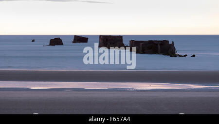 Parti dei resti del porto di Mulberry sulla spiaggia d'oro Asnelles Calvados Normandia catturati al tramonto Foto Stock