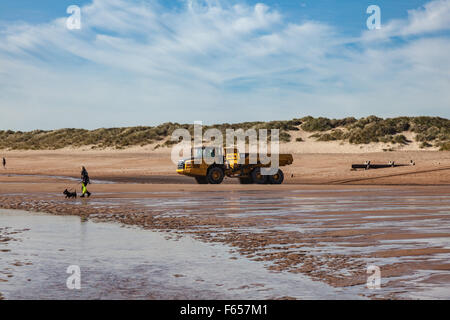 Dog walker sulla sabbiosa spiaggia di Blyth, Northumberland, Regno Unito Foto Stock