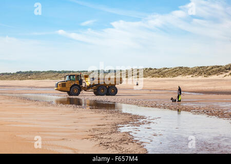 Dog walker sulla sabbiosa spiaggia di Blyth, Northumberland, Regno Unito Foto Stock