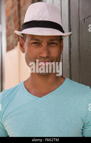 Ritratto di un ambiguo etnicamente uomo che indossa una fedora e luce maglia verde all'esterno. Foto Stock